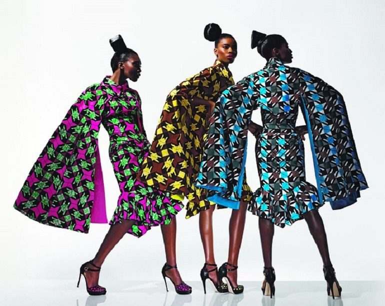 Image: Three beautiful women show off their dresses made from with wax printed fabrics with bold patterns that have been described as Authentic African Fabric