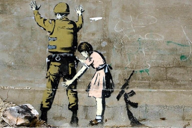 Image: Girl and a Soldier on the West Bank Wall by Banksy, is an example of how the artist explores street art and graffiti art to make statements about war, liberty and important social issues. Banksy Art