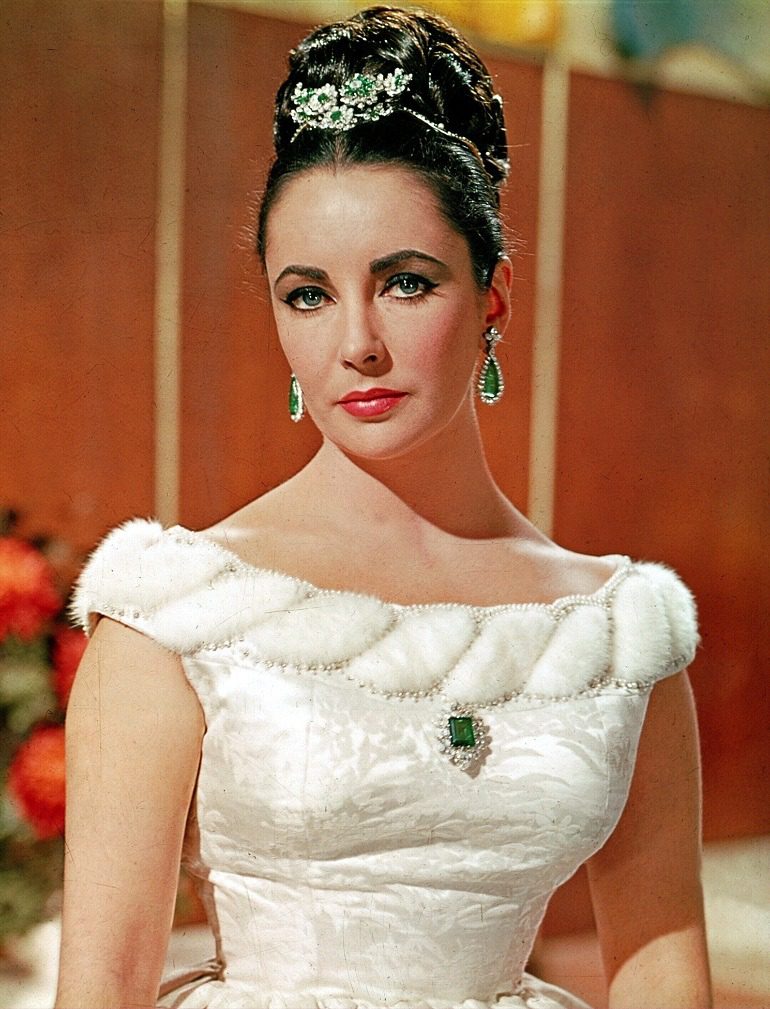 Image: Elizabeth Taylor wearing her Bulgari platinum, emerald and diamond tremblant brooch, Colombian emerald brooch and matching earrings 1963, some of the jewels on display at NGV