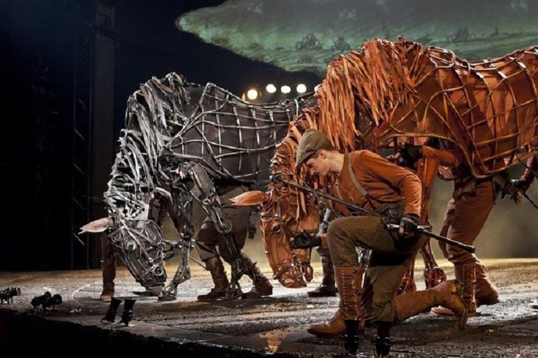 Image: War Horse puppet masters on stage in a depiction of World War I through the eyes of Joey the horse and farm boy Albert