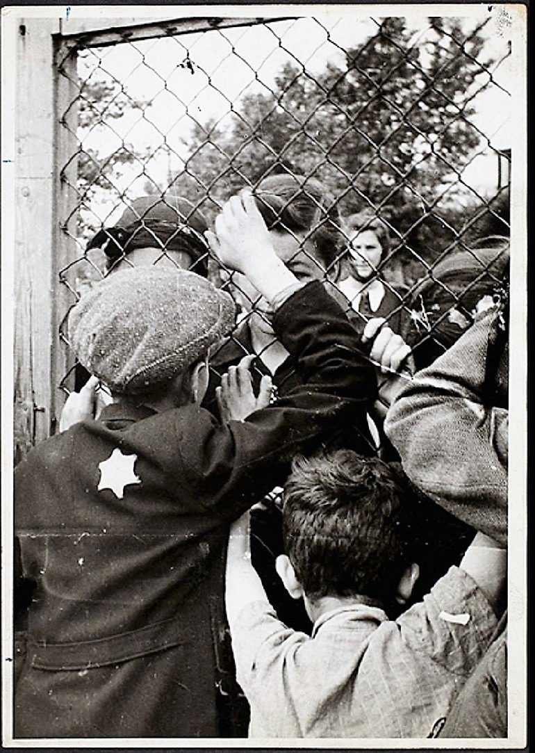 Image: Black and white photograph of Children talking through fence of central prison on Czarnecki Street prior to deportation by Henryk Ross, 1940–42