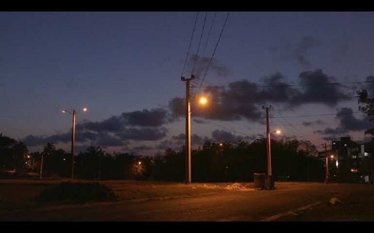 Image: A panoramic view of a city in a still from La botella al mar de María Elena, a 44-minute single channel digital film by Coco Fusco made in 2015