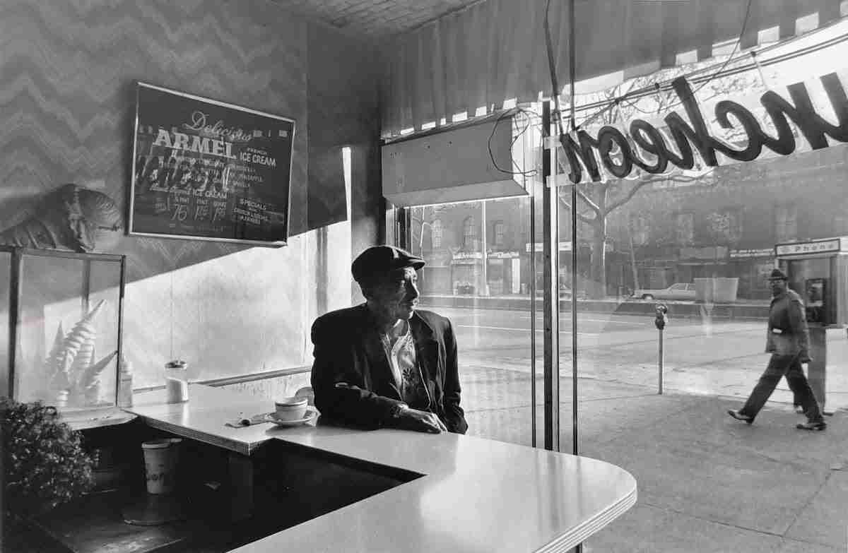 Photograph of a man sitting in a coffee store by by Chester Higgins is one of the images celebrating New York City at the Amory Show