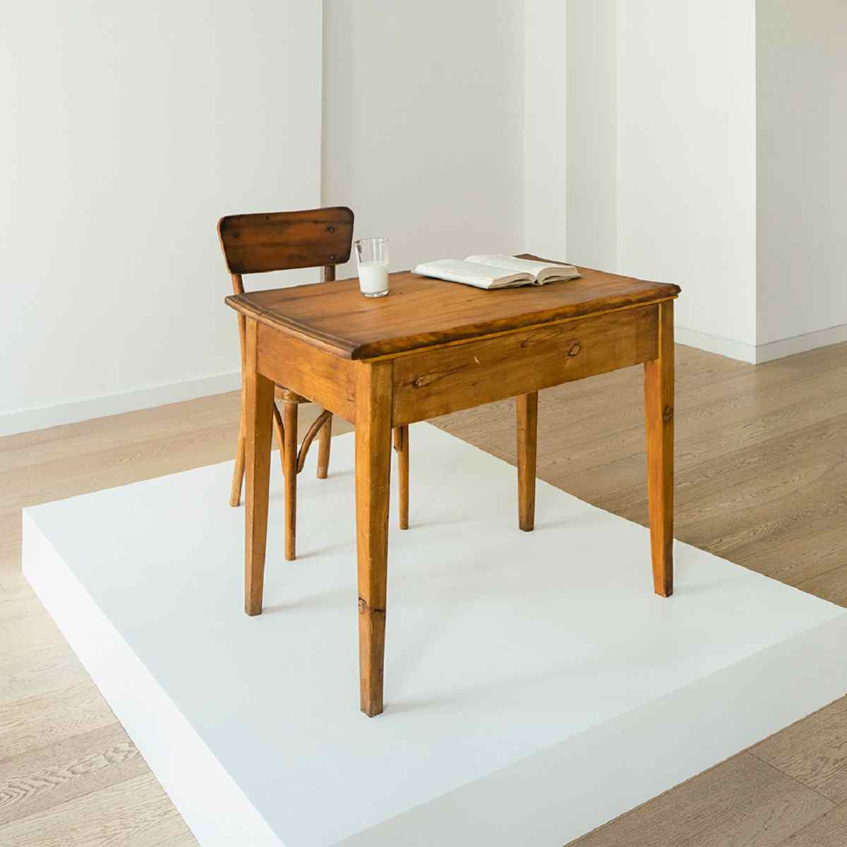A chair, desk, glass of milk an book on pedestal titled Mnḗme by Maayan-Sophia Weisstub is one of the works shortlisted for the UK New Artist competition