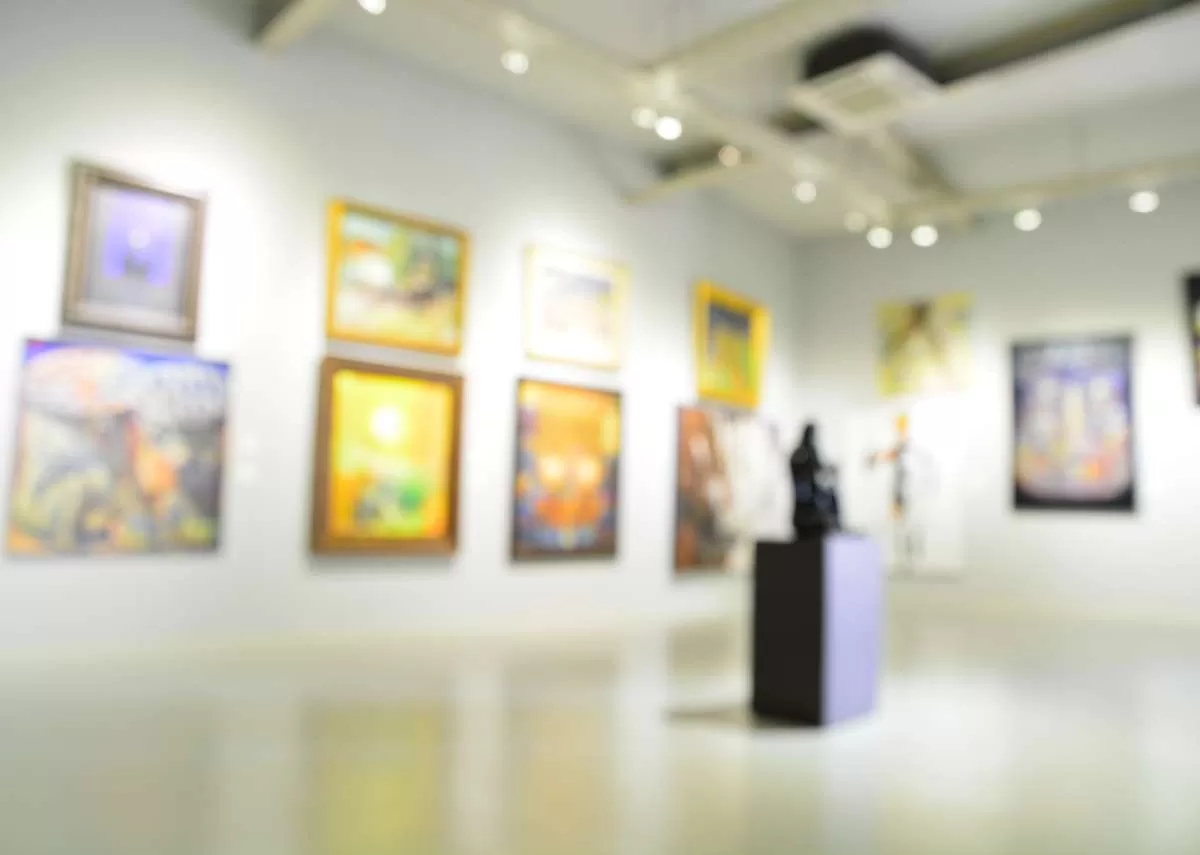 An empty art gallery or museum includes one person in a corner looking at a wall of contemporary hanging art. Indoor climate management is important for the preservation of the artifacts
