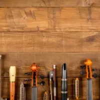 A group of various types of instruments lying in a row over a wooden background. You can only see their top halves. Taking care of your instrument is a great way to make it last longer