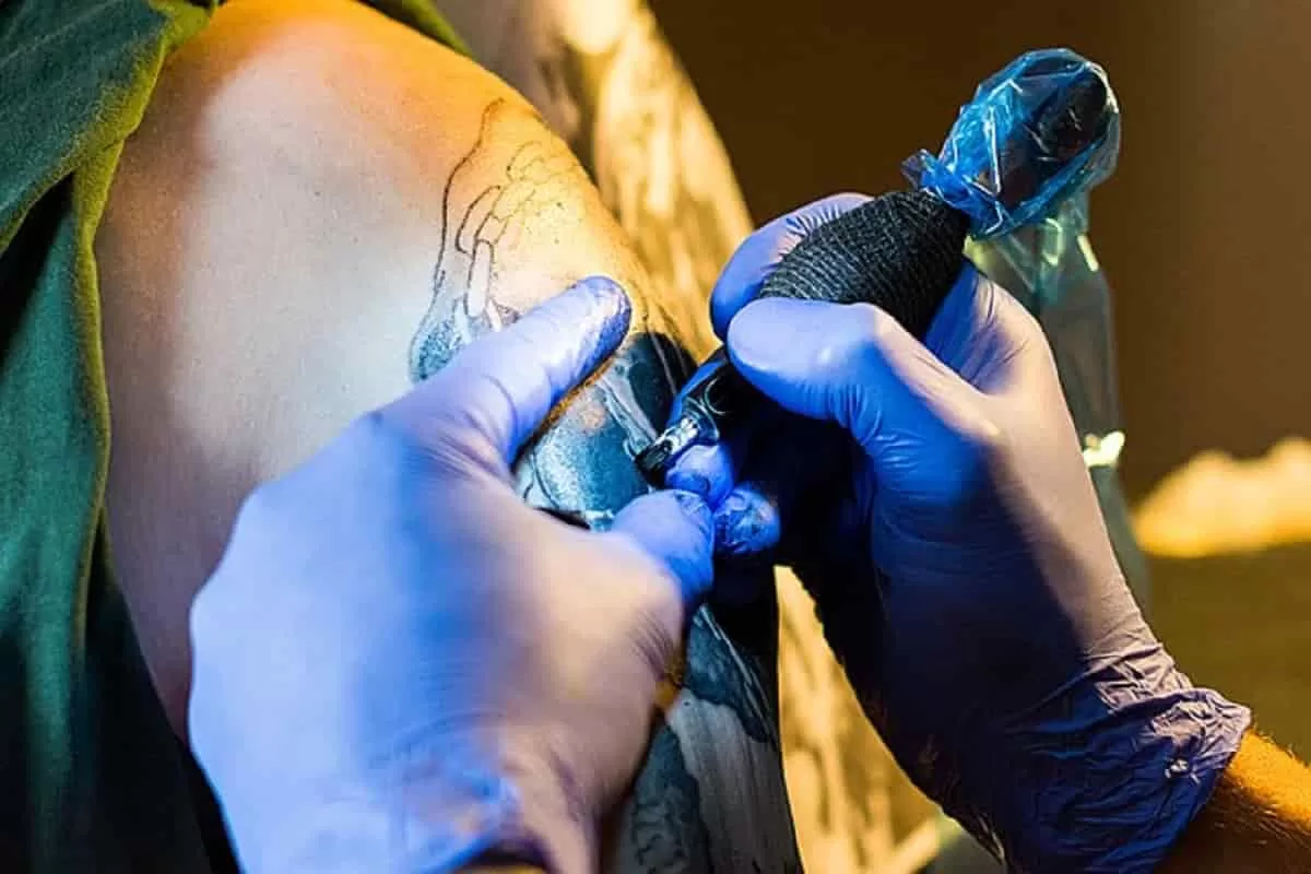 A tattoo artist at work. Intense focus and understing of how a tattoo fits the body is how tattoo artists perfect their craft.