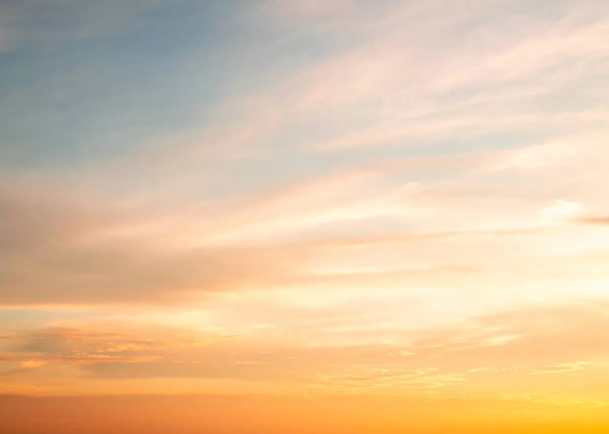A blanket of clouds across the sky in sunset. The sky’s colors shift from a vibrant yellow-orange to a gentle blue hue. It is important to understand why photographs of the sky rarely capture its color.