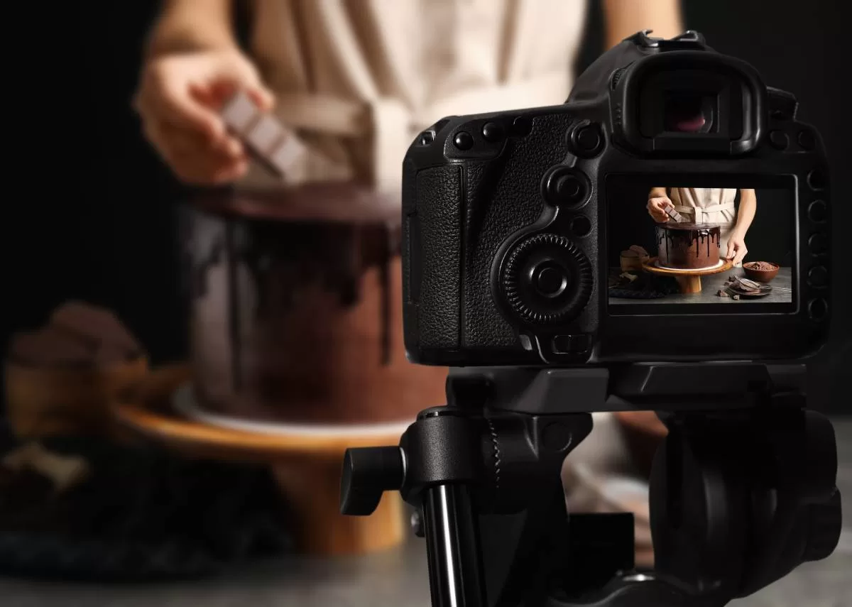 A studio area with a chef preparing to photograph a chocolate cake with a black curtain background. Capturing the beauty of desserts requires knowing how to effectively capture these sweet masterpieces