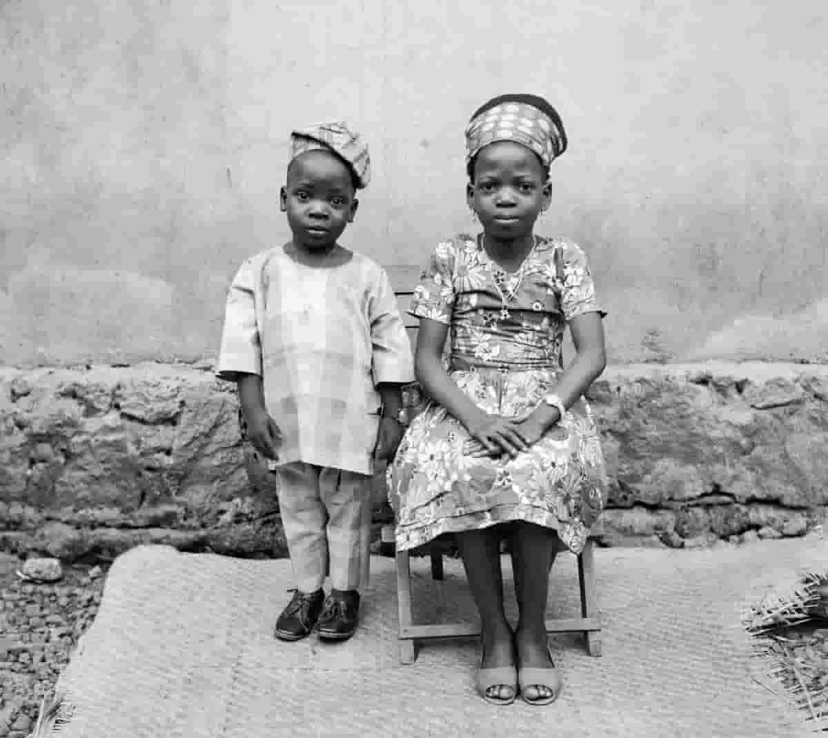 Two children dressed in traditional attire pose for a photograph at the Abi Morocco Photos studio on Aina Street, Shogunle, Lagos, c. 1970s. This is one of images from the Lagos Studio Archives