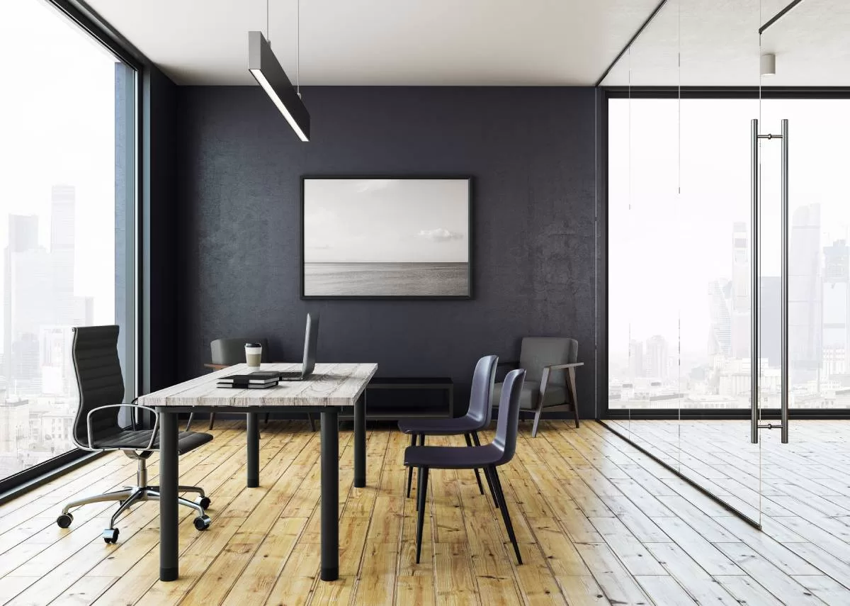 A large black-and-white photograph acting as the statement piece on a dark wall of a bright, airy office.