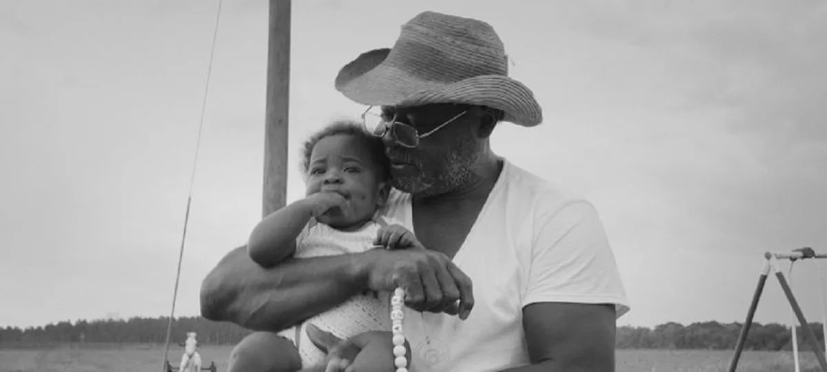 A Black farmer holds a baby in Seeds, the Full Frame Documentary Film Festival Grand Jury Award winner