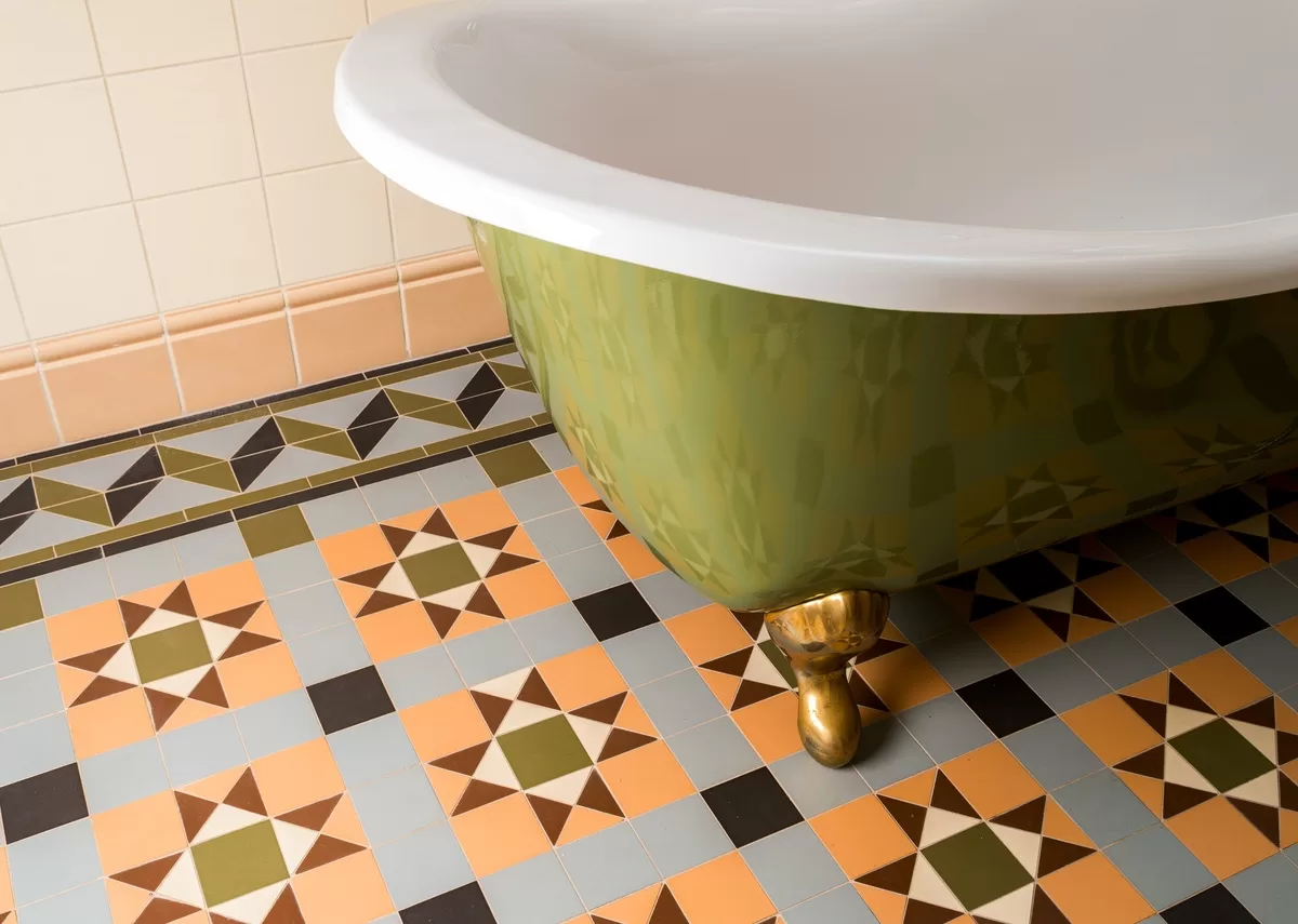 A close-up of a bathroom floor with a geometric tile pattern. The bathroom also has a green freestanding tub. This is one of the unique ideas to add artistic flair to your bathroom.