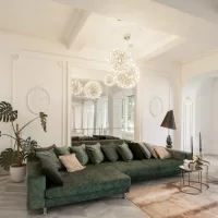A modern, cute, and glamourous interior design with a forest green couch and white background with a rounded chandelier.