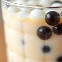 Close-up of a meticulously prepared glass of Taichi bubble tea, showing a clear distinction between the milk tea layer and the unique colorful 'Taichi,' pearls half white, half black. These common questions about Taichi Bubble Tea Answered to help you make a better choice.