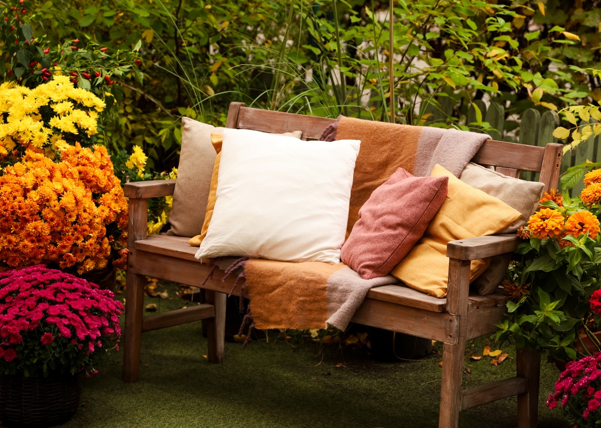 Cozy garden seating with colorful flowers and soft cushions, creating a bright and inviting outdoor retreat.
