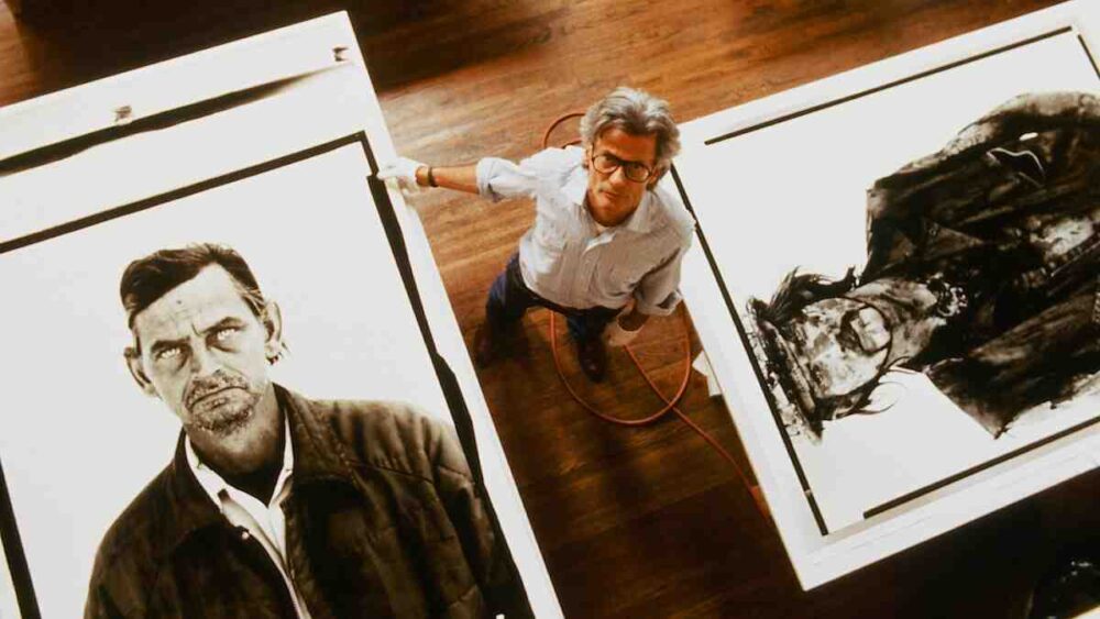 Netflix-Richard-Avedon-documentary: Richard Avedon standing in his studio surrounded by several of his iconic portrait prints.